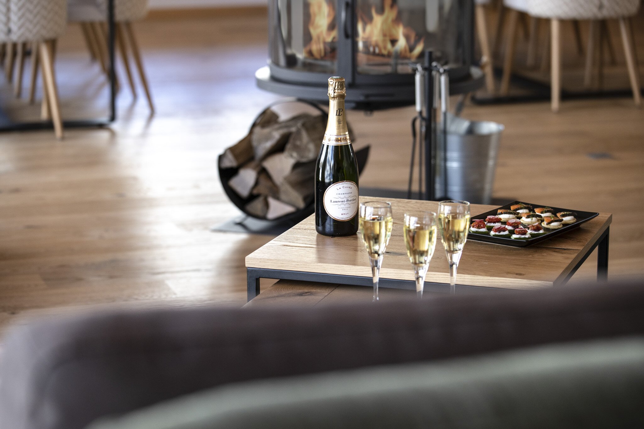 Champagne and canapes on a table, fire lit behind, in No 8 CLUB Bellevarde, Val d'Isere