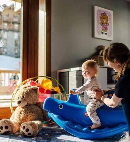 VIP SKI nanny with young toddler playing on plastic ride on rocking toy
