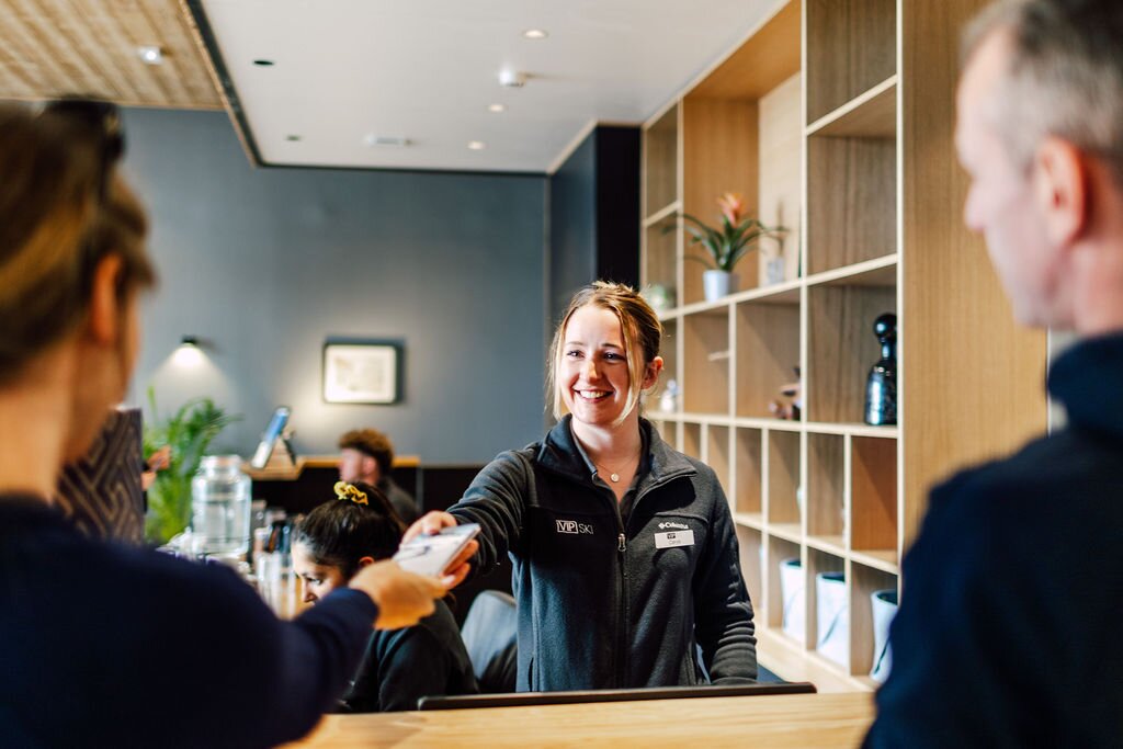 Smiling VIP SKI reception staff handing over room key at Bear Lodge ski hotel in Les Arcs