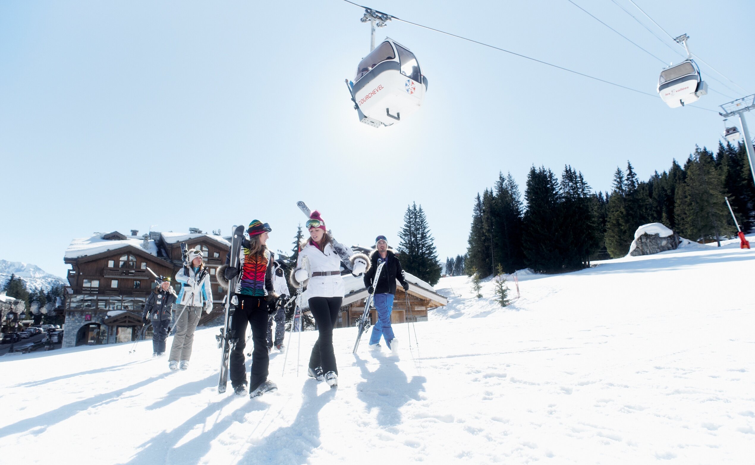 Skiers walking across ski slope carrying skis