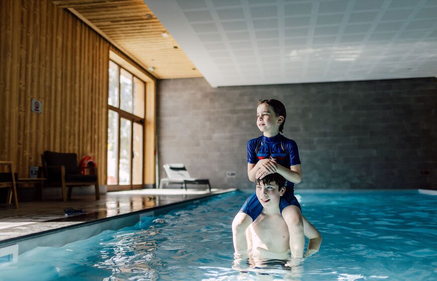 Two brothers playing in swimming pool at Bear Lodge ski hotel in Les Arcs