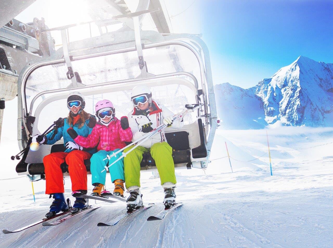 Two smiling adults and a child getting off a chairlift